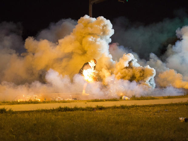 A protester throws back a smoke bomb while clashing with police in Ferguson, Missouri, Aug. 13, 2014. 