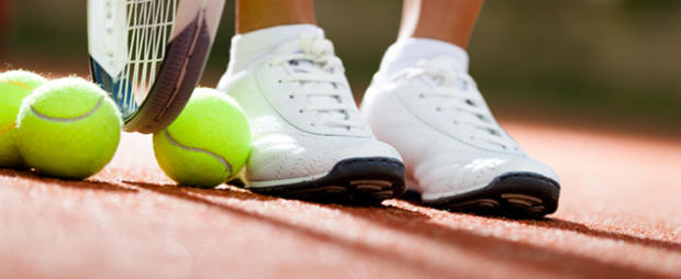 Legs of athlete near the tennis racket and balls 