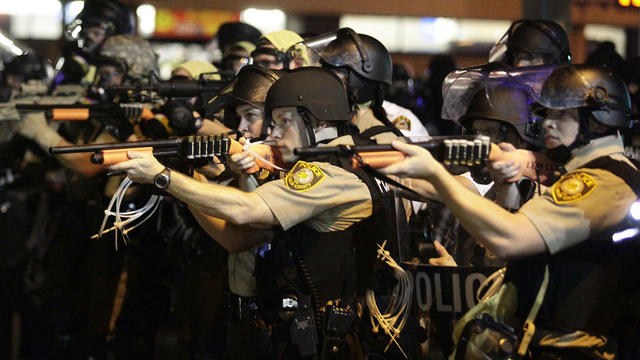 Police officers point their weapons at demonstrators protesting against the shooting death of Michael Brown in Ferguson, Missouri, Aug. 18, 2014. 