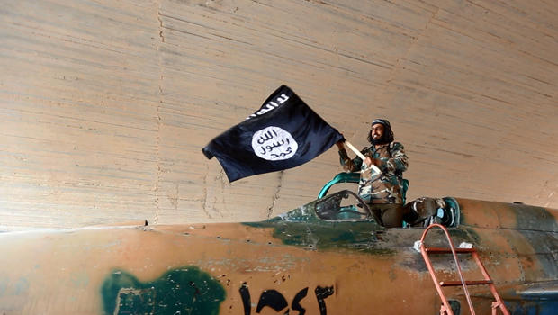 A fighter of the Islamic State of Iraq and Syria, or ISIS, waves the group's flag from inside a captured government fighter jet following the battle for the Tabqa air base, in Raqqa, Syria, in this undated image posted Aug. 27, 2014. 