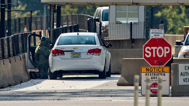 An explosive technician in a bomb suit kneels as he searches a vehicle near the entrance to the White House in Washington Sept. 20, 2014. 