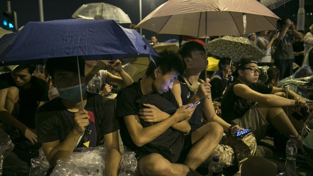 Protesters take shelter from the rain as they sit overnight outside the legislative government complex in Hong Kong 