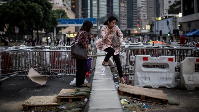  Two women walk over makeshift stairs at a road barricade blocking a main road into the pro-democracy protest site 