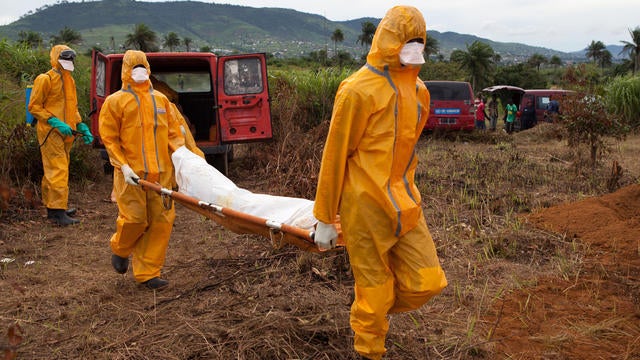 Volunteers in protective suit carry for burial the body of a person who died from Ebola in Waterloo, some 16 miles southeast of Freetown 