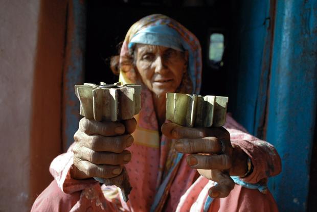 Woman holds mortar shell that damaged her village. 