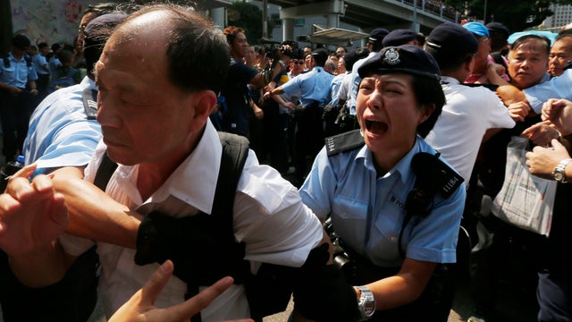 A policewoman reacts as she stops an anti-Occupy protester from breaking a police cordon to charge at pro-democracy protesters during a confrontation in Hong Kong 