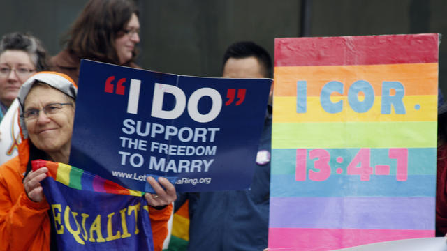 Lin Davis, of Juneau, Alaska, holds signs supporting gay marriage during a news conference outside the federal courthouse in Anchorage 