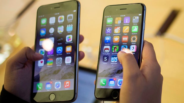 A customer holds an iPhone 6, right, and iPhone 6 Plus at the Apple store on Fifth Avenue after the phones went on sale in New York Sept. 19, 2014. 