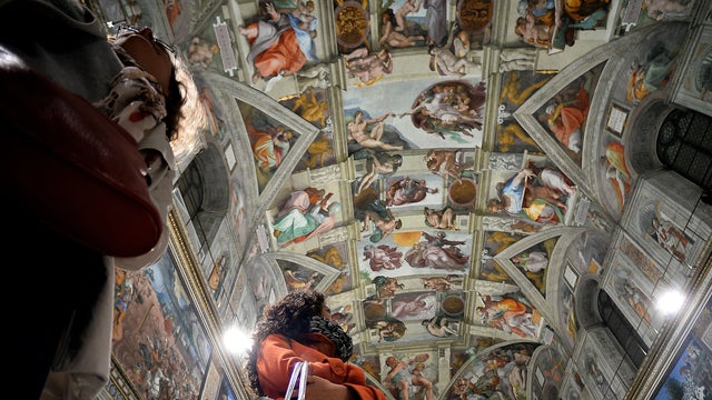 Journalists stare at the Sistine Chapel with its new lighting during a press visit at the Vatican Oct. 29, 2014. 