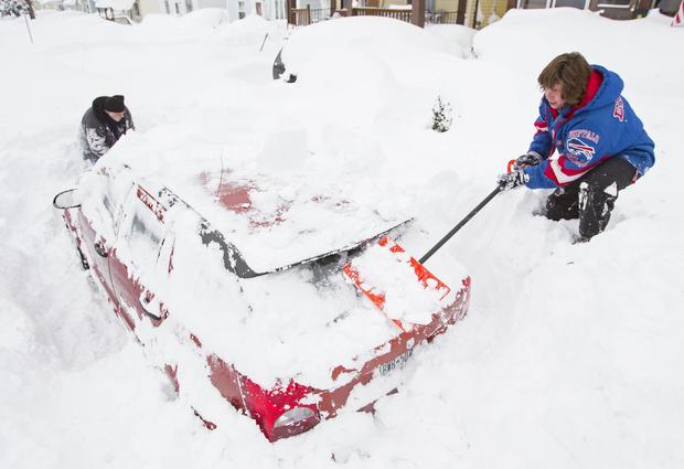 Lori and Bob Weishaar shovel snow from around their vehicle following an autumn storm in Buffalo, N.Y., Nov. 20, 2014. 