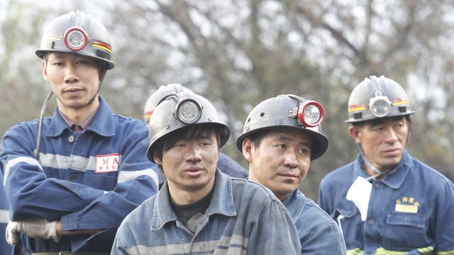Miners wait for their brothers at a flooded coal mine where 22 miners were trapped underground in Qujing, Yunnan Province 