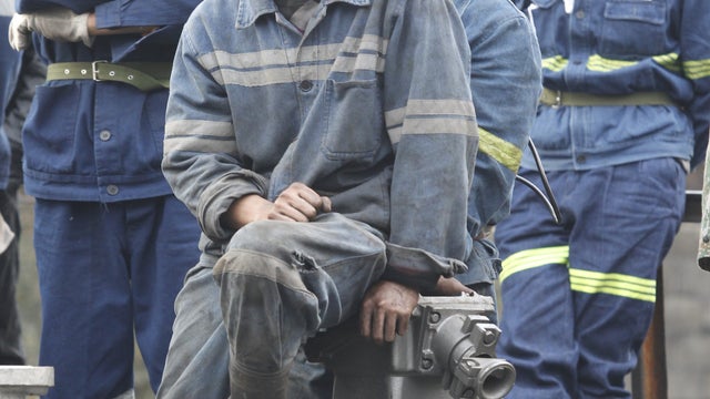 Miners wait for their brothers at a flooded coal mine where 22 miners were trapped underground in Qujing, Yunnan Province 