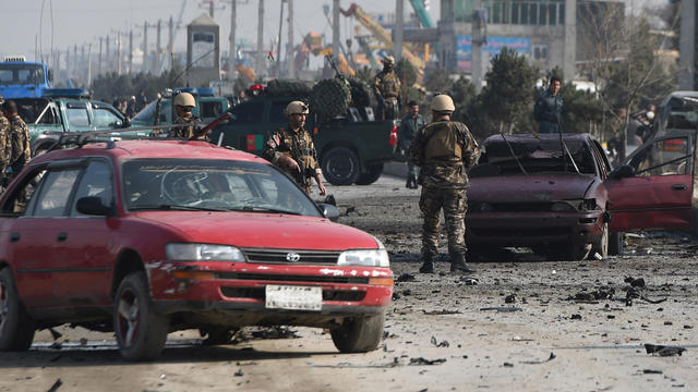 Afghan intelligence personnel inspect the site of a suicide attack on a British embassy vehicle 