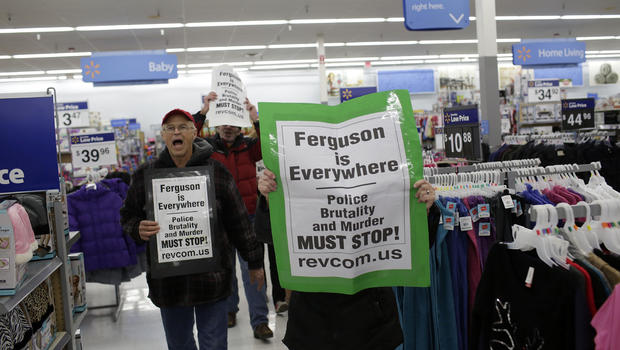 Demonstrators protesting the shooting death of Michael Brown hold signs as they walk through a local Wal-Mart store on Black Friday, Nov. 28, 2014, near Ferguson, Missouri. 