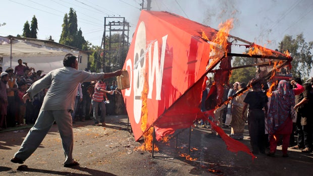 A demonstrator throws kerosene oil on an effigy depicting Dow Chemical Company, which now owns Union Carbide, to burn it during a protest to mark the 30th anniversary of the Bhopal gas tragedy in Bhopal, India, Dec. 3, 2014. 