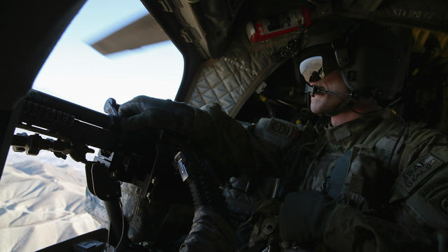 A U.S. Army Airborne CH-47 Chinook window gunner looks out while flying behind Defense Chuck Hagel's helicopter in Afghanistan 