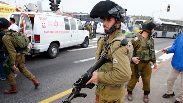 An Israeli soldier stands at the scene where a Palestinian attacked civilians with acid near the West Bank Jewish settlement of Neve Daniel, part of the Gush Etzion bloc, Dec. 12, 2014. 