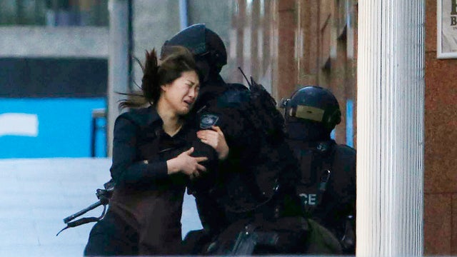 A hostage runs towards a police officer outside Lindt cafe, where other hostages are being held 