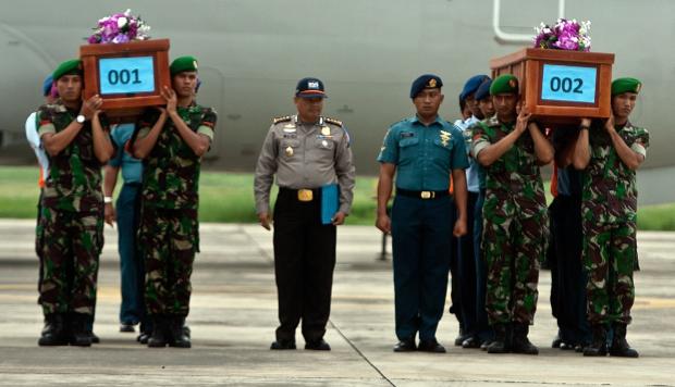 Indonesian military personnel carry coffins of victims recovered from AirAsia flight QZ8501, upon their arrival at the military airbase in Surabaya 