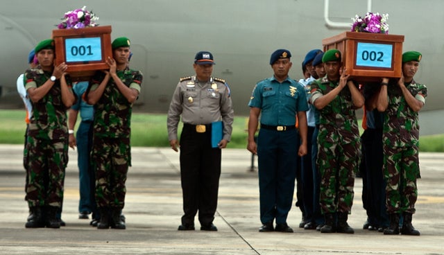Indonesian military personnel carry coffins of victims recovered from AirAsia flight QZ8501, upon their arrival at the military airbase in Surabaya