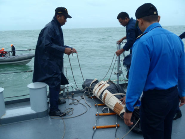 The remains of a victim from AirAsia Flight 8501 is brought on board the Royal Malaysian Navy ship KD Lekir 