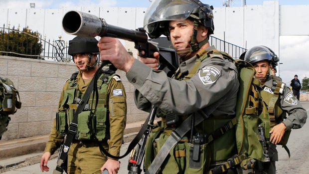 An Israeli border police officer aims his weapon at protesters during a demonstration against the Israeli settlements and demanding for free movement for the Palestinians during Christmas, near a checkpoint in the West Bank city of Bethlehem Dec. 23, 2014 