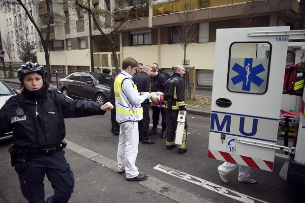 Firefighters carry an injured man on a stretcher in front of the offices of the French satirical newspaper Charlie Hebdo 