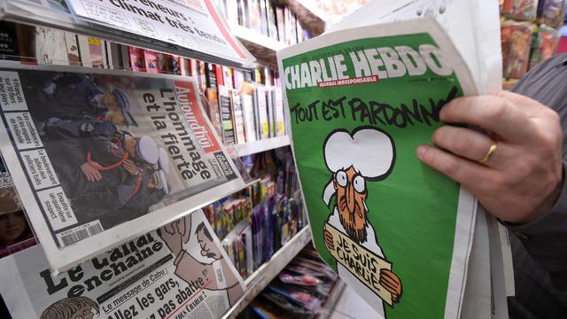 A man displays the latest edition of French satirical magazine Charlie Hebdo shortly after it went on sale on Jan. 14, 2015. 