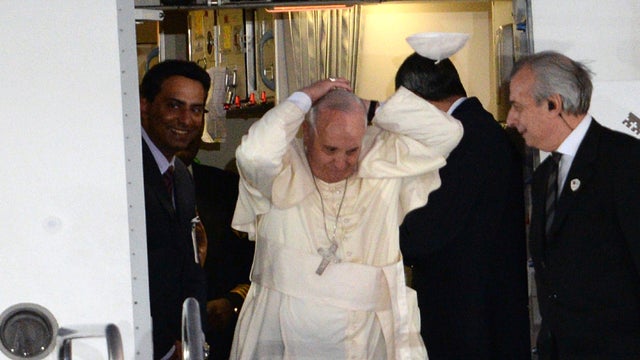 Pope Francis tries to hold on to his cap after it was blown by wind as he disembarks from his plane after arriving at a military airbase in Manila on Jan. 15, 2015. 