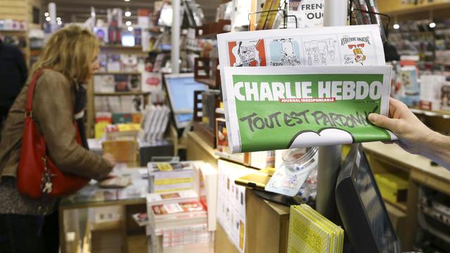 Employee at bookstore holds up copy of satirical French weekly Charlie Hebdo entitled "Tout est pardonne" ("All is forgiven") on January 15, 2015 