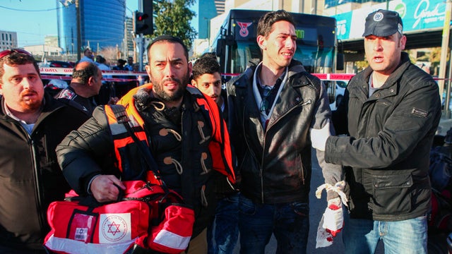 An Israeli medic and a police officer escort a wounded man at the scene of a stabbing attack in Tel Aviv 