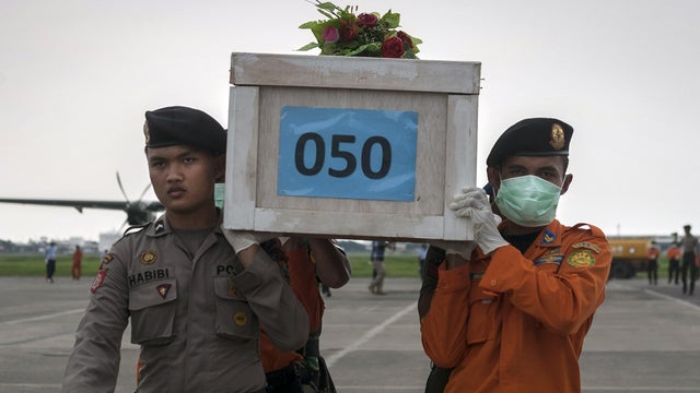 Indonesian soldiers and rescuers carry a coffin on Jan. 19, 2015 bearing the remains of "body number 50" recovered by Indonesian Navy divers from the underwater crash site of AirAsia flight QZ8501. 