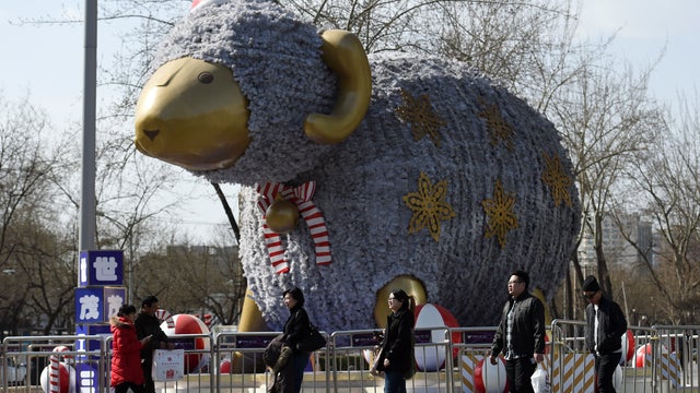 People walk past a giant sheep outside a shopping mall as part of decorations for the upcoming Lunar New Year in Beijing on Feb. 16, 2015.  