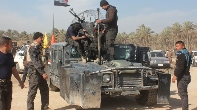 Iraqi soldiers and pro-government militiamen check a machine gun mounted on an armored vehicle stationed near the town of Muqtadiyah  
