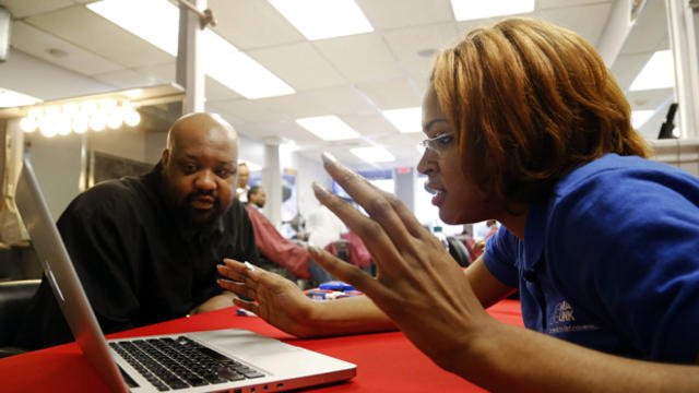 Karima Williams of DC Health Link assists barber Cornel Henry with health insurance information during an event for National African American Enrollment Week of Action, an initiative of the White House and U.S. Department of Health and Human Services, at  