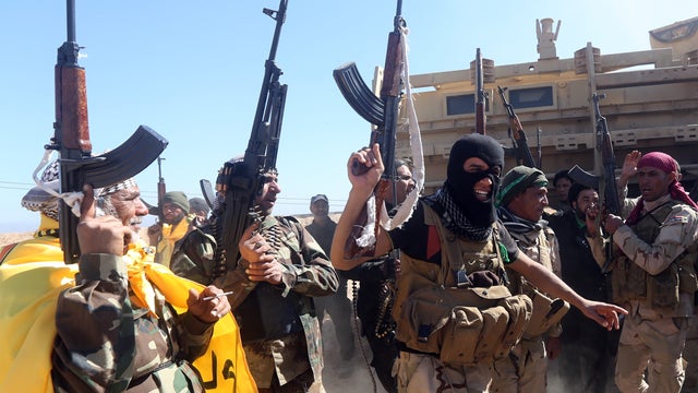 Iraqi pro-government fighters celebrate as they advance into Tikrit, 80 miles north of Baghdad, during a military operation to retake the city from ISIS 