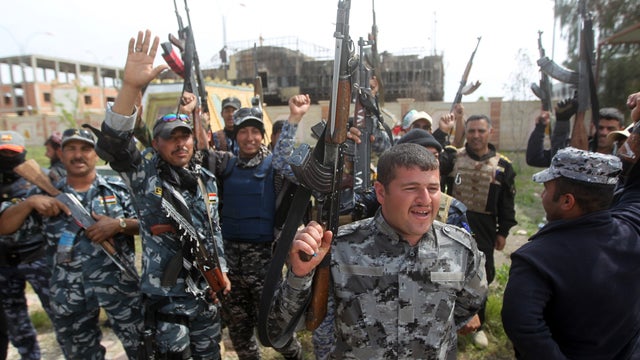 Iraqi security forces and Shiite fighters from the Popular Mobilization units celebrate outside the provincial council building in Tikrit 