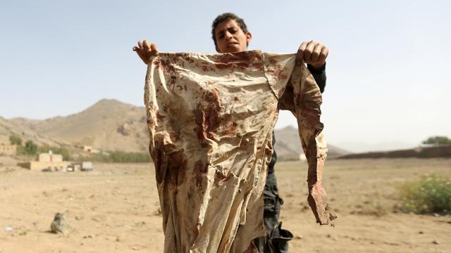 A boy holds a blood-stained garment at the site of an air strike on a house, in Bait Rejal village west of Yemen's capital Sanaa.  