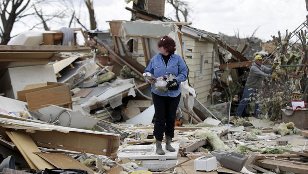 A woman holds her belongings after searching through the debris of a home that was destroyed by a tornado in Rochelle, Illinois, April 10, 2015. 