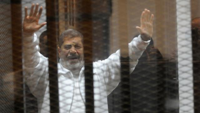 Egypt's deposed president Mohamed Morsi waves from inside the defendants cage during his trial 