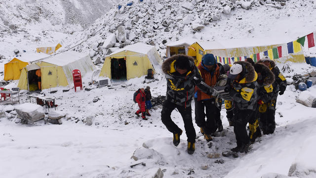 An injured person is carried by rescue members to be airlifted by rescue helicopter at Everest Base Camp 