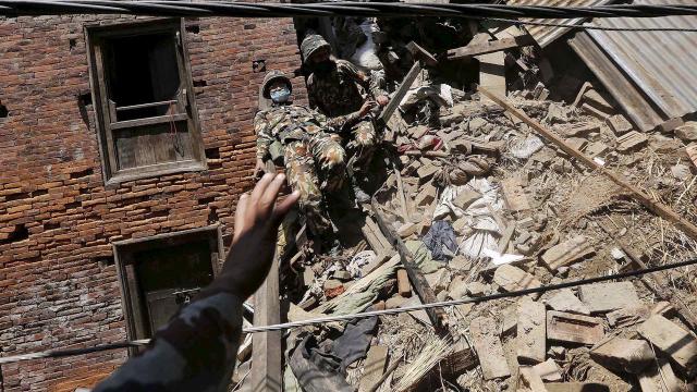 A Nepalese army soldier loses his balance while descending from a mound of rubble in Bhaktapur, Nepal, during the recovery of a body from a house after an earthquake 