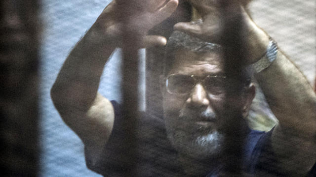 Egypt's deposed Islamist president Mohammed Morsi raises his hands from behind the defendant's cage as the judge reads out his verdict sentencing him and more than 100 other defendants to death at the police academy in Cairo May 16, 2015. 