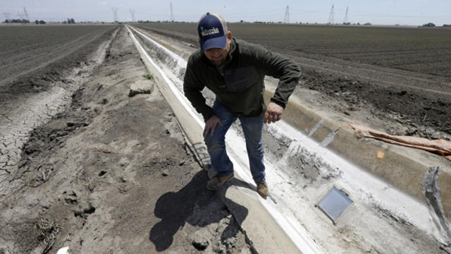 Farmer Gino Celli climbs out of a irrigation canal that is covered in dried salt on a field he farms near Stockton, Calif., May 18, 2015. 