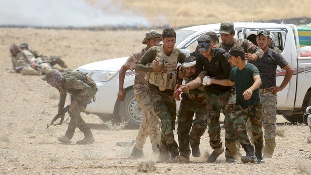 Iraqi Shi'ite paramilitaries help a wounded fighter after clashes with Islamist State militants in al Nibaie, in Anbar province 