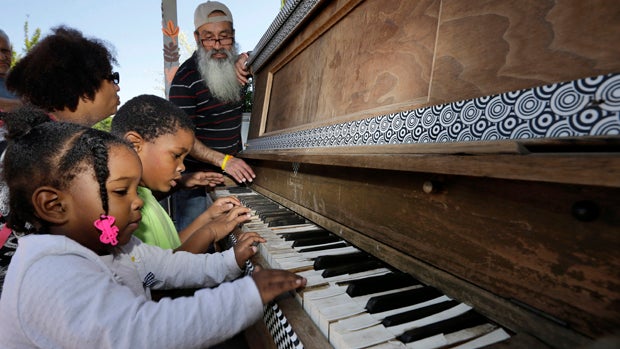 ​As Anyalise Boykin, 2, and her brother, Noah Boykin, 5, play a piano set up in front of City Hall, their mother, Deborah Boykin, talks with Reinaldo Suarez in Camden, N.J., May 26, 2015. 