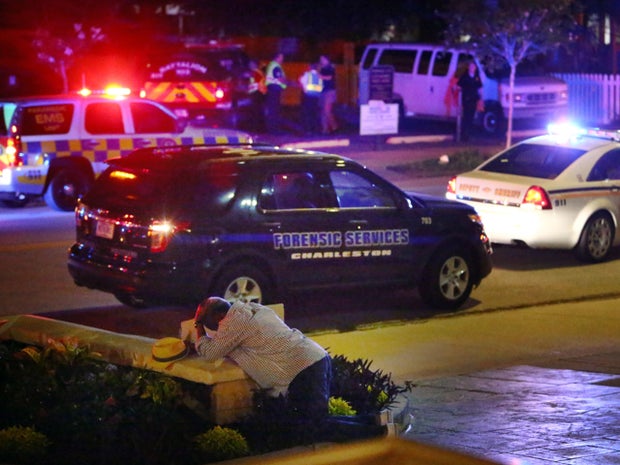 Man kneels across the street from where police gathered outside Emanuel AME Church following shooting on night of June 17, 2015, in Charleston, S.C.