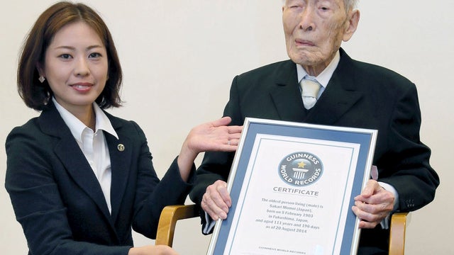 Sakari Momoi (R) receives a Guinness World Records certificate in 2014 naming him as the world's oldest man at 111 years of age, in Tokyo 