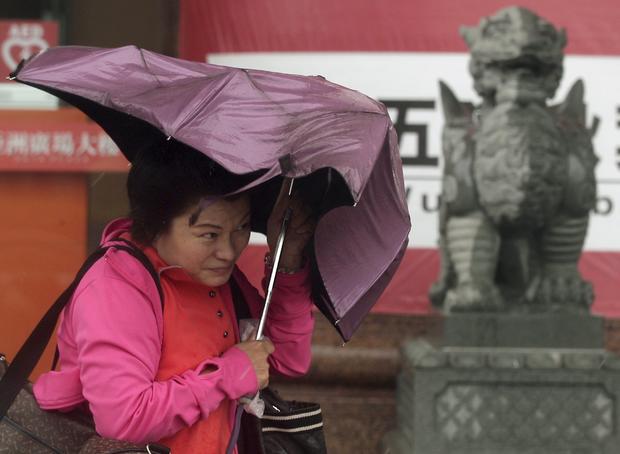 A woman holds her umbrella while walking against strong winds as Typhoon Chan-hom approaches Taiwan, in Taipei 