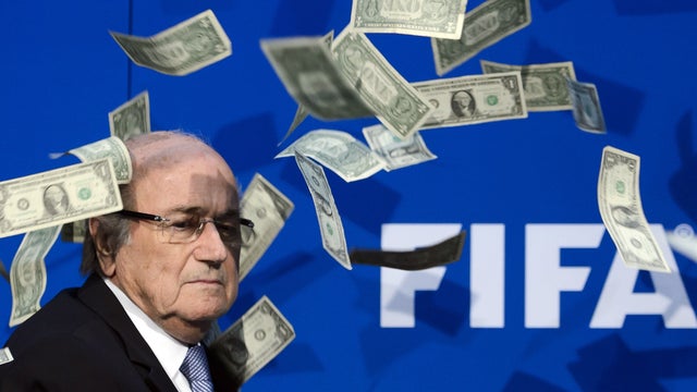 FIFA president Sepp Blatter looks on with fake dollars note flying around him thrown by a protester during a press conference at the football's world body headquarter's in Zurich 